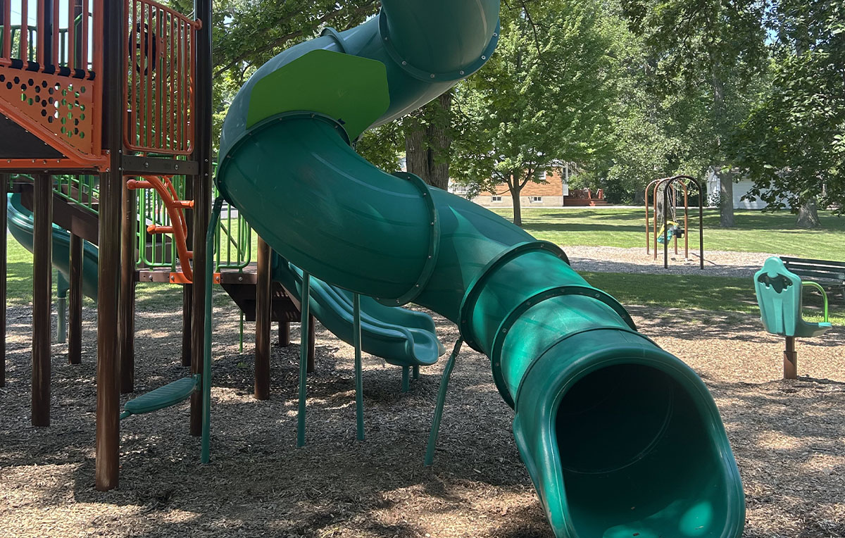 Detail of a vibrant green spiral playground slide, part of an Allsite Services recreational equipment installation.